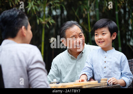 Drei Menschen Schach spielen zwischen den beiden Generationen Stockfoto