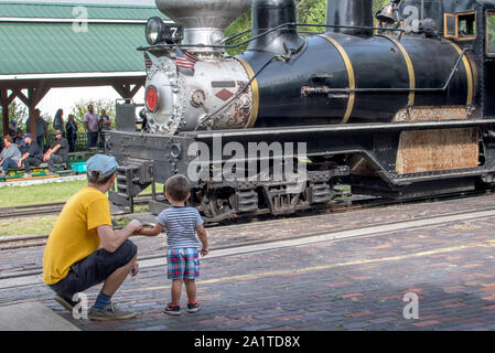 Hesston IN USA, 31. August 2019; Vater und Sohn zusehen, wie eine alte Dampflok zieht in den Bahnhof am Hesston Train Museum. Stockfoto