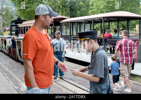 Hesston IN USA, 31. August 2019; ein junger Dirigent stanzen Tickets ist ein Mann, damit er und seine Familie eine Fahrt mit dem Zug am Hesston Train Museum nehmen können Stockfoto