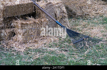 Ein Rasen rake Lügen gegen Heuballen auf einem lokalen Farm in Indiana, USA Stockfoto
