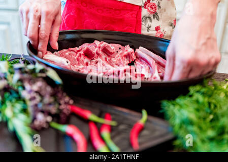 Nahaufnahme, Hände von Cook, Stücke von raw Hammel Rippen auf Pfanne Stockfoto