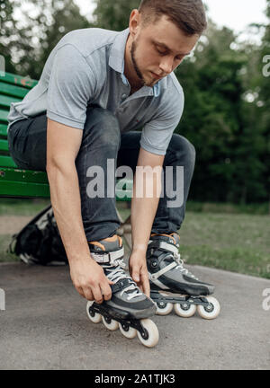 Roller Skating, männliche Skater setzt auf Skates in Park Stockfoto