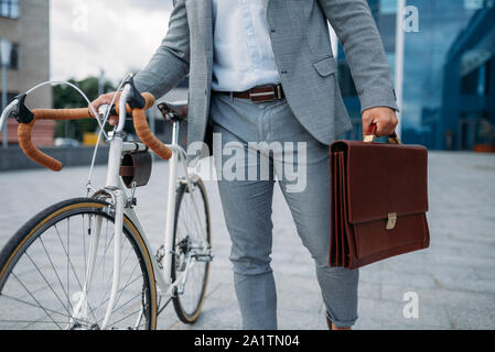 Geschäftsmann mit Tasche und Fahrrad in der Innenstadt Stockfoto