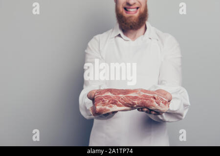 Close-up 7/8 Foto Portrait von er schön schön schön heiter Metzger guy Holding mit Fleisch Stück in den Armen Hände bereit, lecker zubereiten Stockfoto