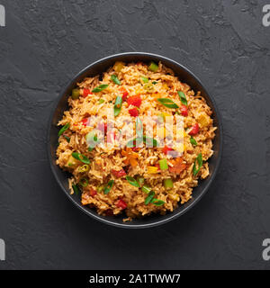 Veg Schezwan gebratener Reis in schwarz Schüssel am dunklen Schiefer Hintergrund. Vegetarische Szechuan Reis ist indo-chinesischen Küche Teller mit Paprika, Grüne Bohnen, Stockfoto