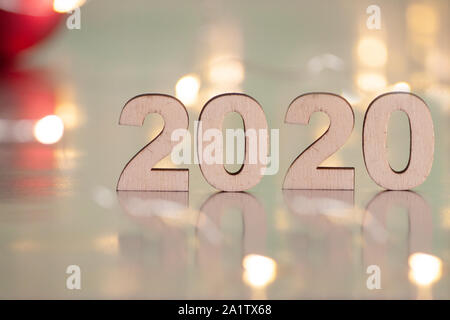 Die Inschrift 2020, Neujahr und Weihnachten, von hinten unscharf Lichtpunkte auf einem blauen Hintergrund und rote Kugeln auf dem Weihnachtsbaum. Weihnachten ein Stockfoto