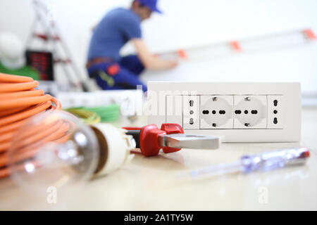 Elektriker Arbeiten mit elektrischen Geräten im Vordergrund, Birne, Werkzeuge und Sockel, Stromkreise, elektrische Verkabelung Stockfoto