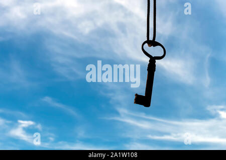 Antike Schlüssel hängen an einem Seil gegen einen schönen blauen Himmel mit einigen Wolken Stockfoto