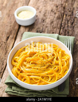 Fettuccine Pasta mit frischen hausgemachten cremige Kürbis alfredo Sauce garniert mit frisch gemahlenem schwarzem Pfeffer und in Schüssel serviert. Stockfoto