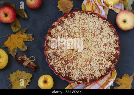 Torte mit Äpfeln wird in eine keramische Form auf einem dunklen Hintergrund, Ansicht von oben entfernt, in der Nähe der horizontalen Ausrichtung Stockfoto