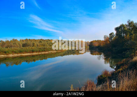 Herbst Landschaft. Bäume sind in der Wasseroberfläche des Flusses reflektiert. Gelbe Blätter fallen auf See. Wasser Landschaft im Herbst. Herbstliche Panorama mit Blick auf den Fluss. Stockfoto