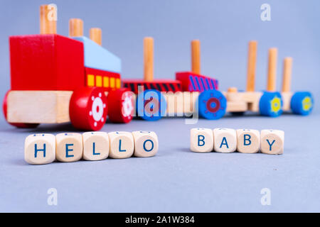 Buchstaben auf der Vorderseite: "Hallo Baby", ein buntes Holz- zug auf der Rückseite - Neugeborene Konzept Stockfoto