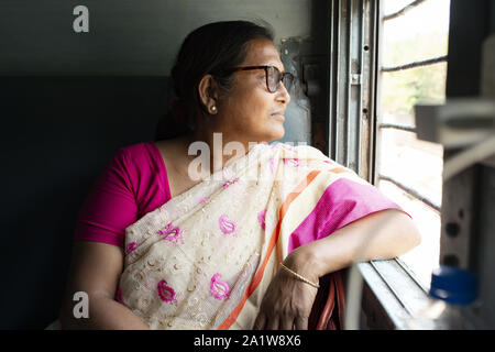 Eine indische Frau ist Blick aus dem Fenster eines indischen Zug, wie sie von Delhi nach Varanasi reist. Stockfoto