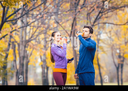 Sport paar Trinkwasser in Pause ausgeführt wird. Stockfoto