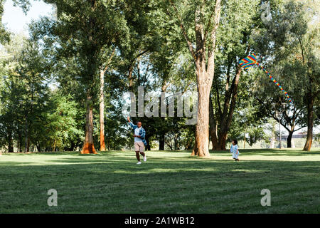 Happy african american Sohn und Vater laufen auf Gras im Park Stockfoto