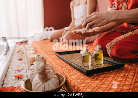 7/8-Ansicht von Masseur gießen Duft Öl auf der Hand Stockfoto