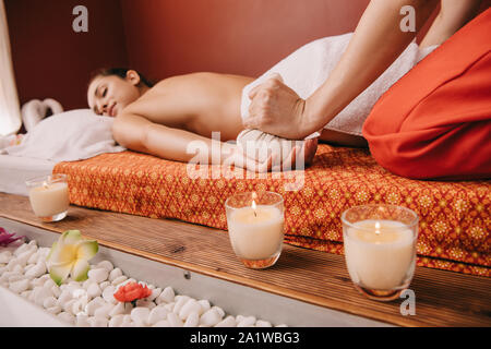 7/8-Ansicht von Masseur, Massage mit herbal Ball zu Frau in Spa Stockfoto