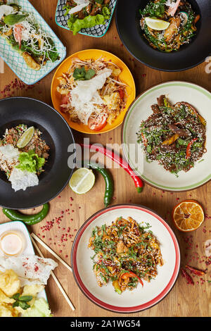 Vor Hintergrund der Ansicht von köstlichen asiatischen Speisen auf hölzernen Tisch dekoriert mit Chili und Kalk einzurichten, kopieren Sie Platz Stockfoto