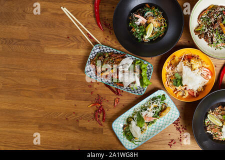 Vor Hintergrund der Ansicht von köstlichen asiatischen Speisen auf hölzernen Tisch dekoriert mit Chili, Kopie Raum Stockfoto
