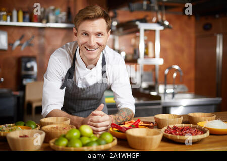 Porträt des zeitgenössischen Chef lächelt Kamera, während mit Gewürzen im Restaurant Küche Posing, kopieren Raum Stockfoto