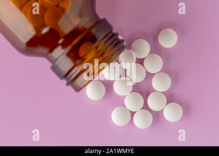 Weiße, runde Tabletten vor Glas Flasche Pillen verstreut Stockfoto