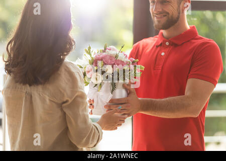 7/8-Ansicht von Happy delivery man Blumen für Frau Stockfoto