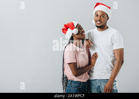 Afrikanische amerikanische Ehepaar in Santa Hüte isoliert auf Grau Stockfoto
