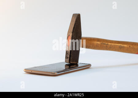 Hammer zertrümmert auf dem alten Handy, zerbrochenes Glas Stockfoto