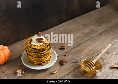 Kürbis Pfannkuchen mit Sahne, Pecan und Honig auf rustikalen Hintergrund, kopieren. Traditionelle herbstliche gesundes Frühstück-Stack von Kürbis panca Stockfoto