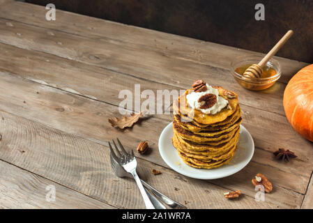 Kürbis Pfannkuchen mit Sahne, Pecan und Honig auf rustikalen Hintergrund, kopieren. Traditionelle herbstliche gesundes Frühstück-Stack von Kürbis panca Stockfoto