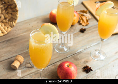 Apple Mimosa Cocktail in hohe Gläser und organische Äpfel auf Holz. Saisonale fallen Getränke für Ferienwohnung Mimosa Champagner Cocktail mit Äpfeln. Stockfoto