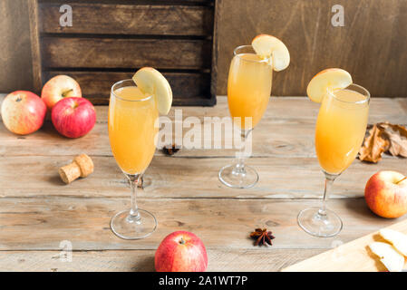 Apple Mimosa Cocktail in hohe Gläser und organische Äpfel auf Holz. Saisonale fallen Getränke für Ferienwohnung Mimosa Champagner Cocktail mit Äpfeln. Stockfoto
