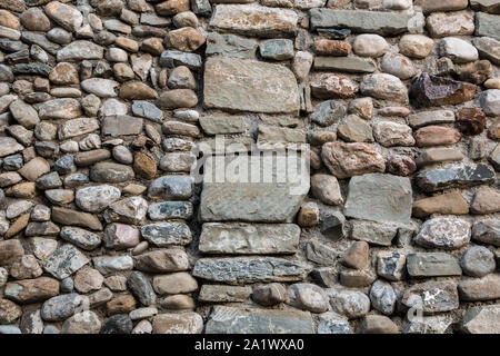 Natursteinmauer mit bunten und unterschiedlich großen Steinen Stockfoto