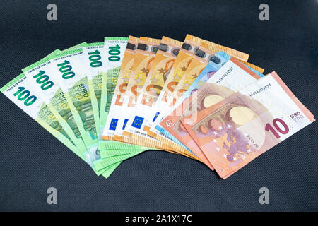 Eine Menge von Euro-banknoten verteilen sich auf einen dunklen Tisch liegend Stockfoto