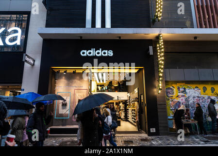 Athen, Griechenland - Januar 4, 2019: Anzeige eines Adidas shop Nachts mit Menschen um in Athen, Griechenland Stockfoto