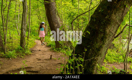 Mittleres Alter Frau mit rosa Pullover gebunden um ihre Taille zu Fuß auf den Weg in den Nationalpark Stockfoto