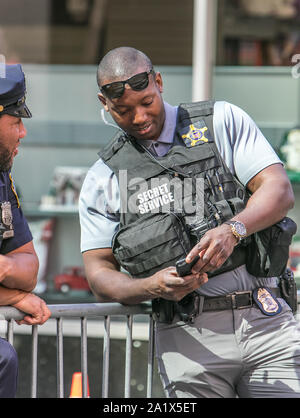 New York City, 27.9.2019: Tall Secret Service Agent sucht bei seinem Telefon bei einer Polizeikontrolle in Manhattan während der UN-Vollversammlung. Stockfoto