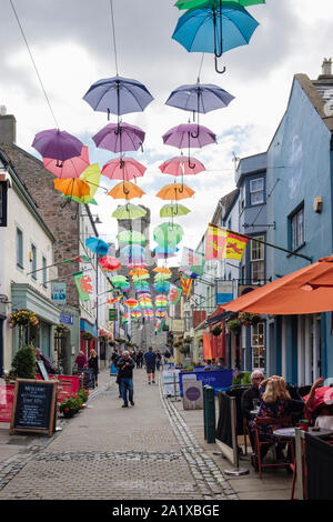 Kunst installation farbenfrohen Display Schirme hängen über einem schmalen alten Straße mit Straßencafés. Palace Street, Caernarfon, Gwynedd, Wales, Großbritannien Stockfoto