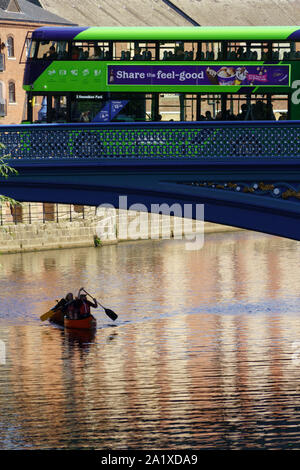 Doppeldeckerbus fährt entlang der Leeds Bridge und Kanufahrer rudern auf dem Aire unter, Leeds, West Yorkshire, England, Großbritannien, Stockfoto