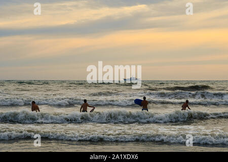 Surfer für die perfekte Welle mit einer Luxusyacht am Horizont bei Sonnenuntergang im Sommer, Lido di Camaiore, Lucca, Versilia, Toskana, Italien warten Stockfoto