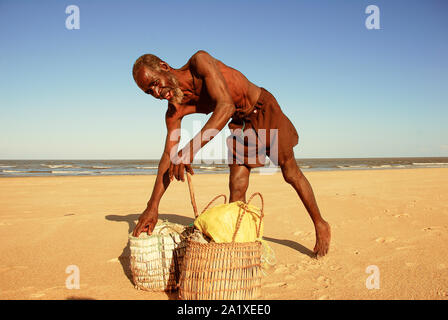 Beira, Sofala, Mosambik - 23. Juli 2006: Lächelnde afrikanische Fischer am Strand mit Stroh Körbe im Sand an einem sonnigen Tag Stockfoto