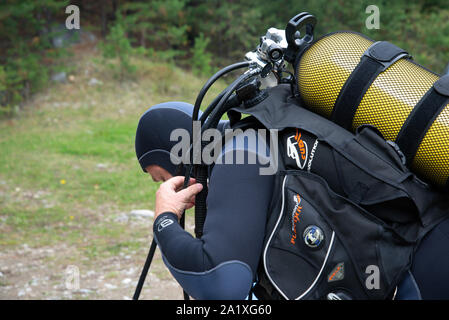 Paayanne See, Finnland - September 2019. Diver prüft Geräte in der Nähe des Sees. Männliche Taucher im Neoprenanzug überprüfen Ausrüstungen vor dem Eintauchen. Stockfoto