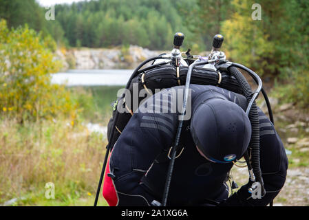 Paayanne See, Finnland - September 2019. Diver prüft Geräte in der Nähe des Sees. Männliche Taucher im Neoprenanzug überprüfen Ausrüstungen vor dem Eintauchen. Stockfoto