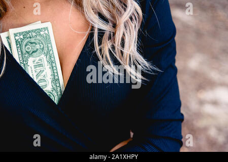 Frau mit einige Dollarscheine in ihr Dekolletee, Konzept der männlichen Chauvinismus. Stockfoto