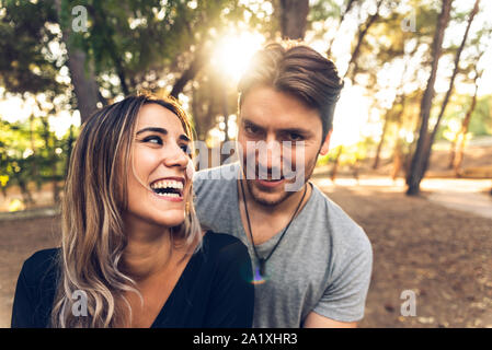 Jungen und Mädchen in der Liebe im Wald lachen während Umarmen vor der Kamera mit warmen Sonnenstrahlen, auf sie konzentriert. Stockfoto