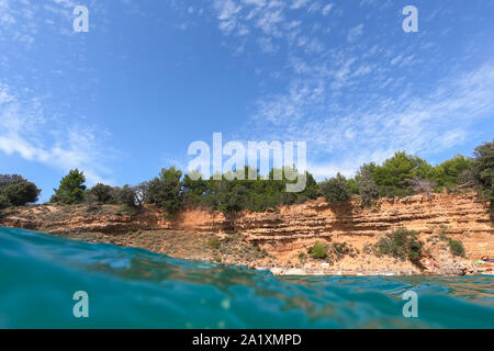 Geteilte Ansicht von Unterwasser- und Seascape Beach Szene, leere Tropischer Strand mit Sand und Felsen an einem schönen sonnigen Tag in Kroatien Stockfoto