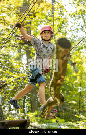 Klettergarten, Kletterkurs, Junge, 9 Jahre alt, mit Helm und Klettergurt, auf einem Kletterkurs in einem Wald, Stockfoto