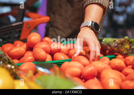 Hand Wahl rote Tomaten in Lebensmittelgeschäft Stockfoto