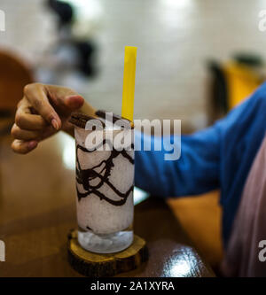 Hände halten hausgemachte Milchshake mit Cookies auf dem Tisch Stockfoto