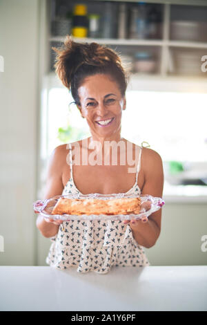 Schöne Frau mittleren Alters auf Küche kochen und lächelnd Stockfoto